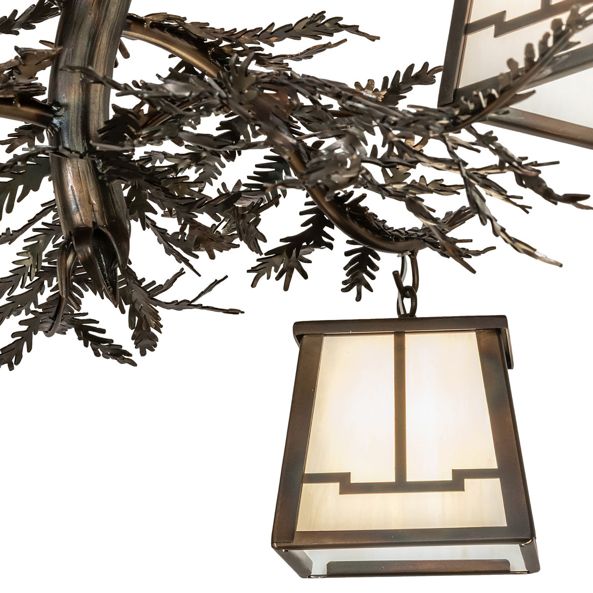 Lantern close-up showing beige iridescent art glass and metal pine branch accents.