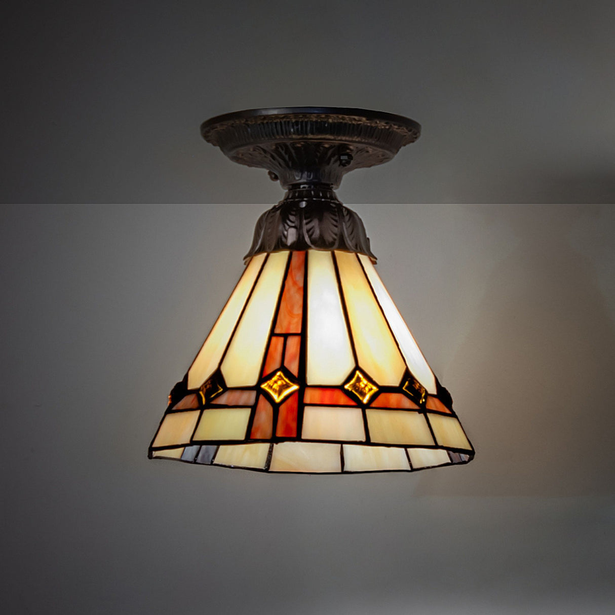 illuminated dark view of pinecone flushmount showcasing vibrant stained glass colors.