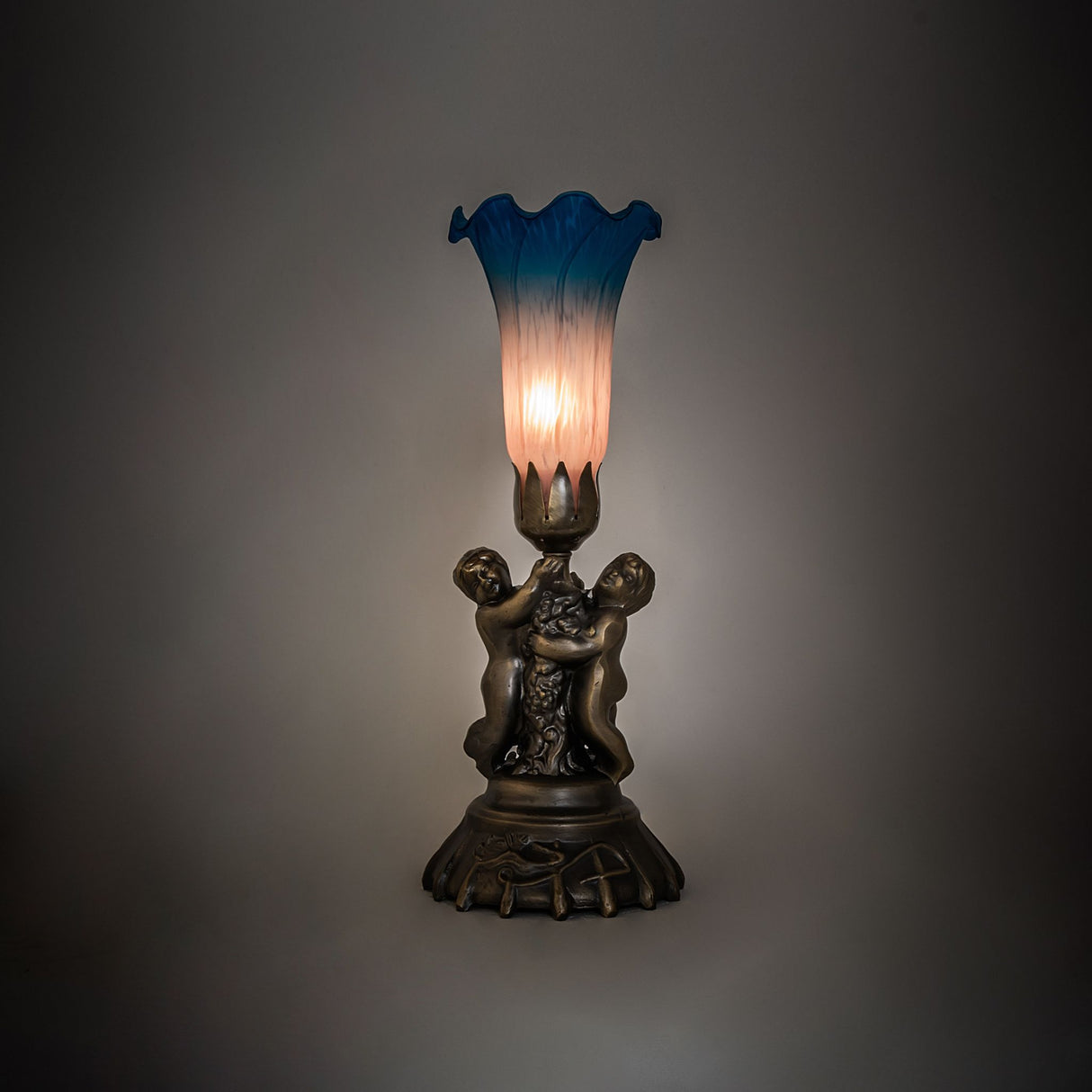 Ambiance view of the Pink and Blue Tiffany Cherub Lamp casting a soft glow.
