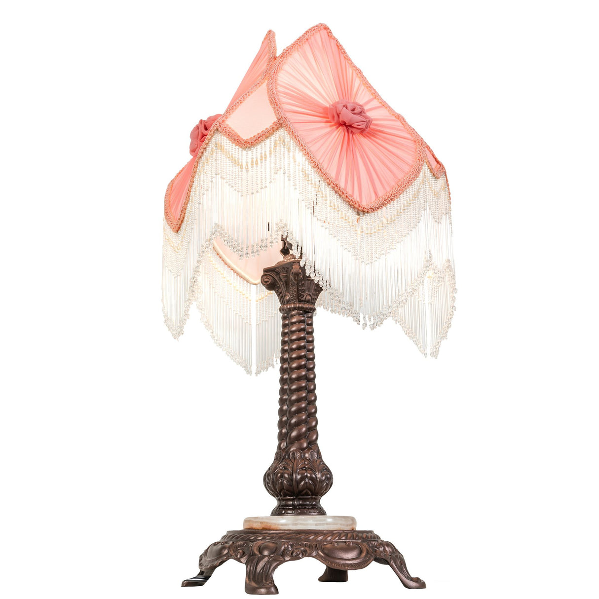 Decorative pink lampshade with fringe detailing atop ornate bronze lamp base.