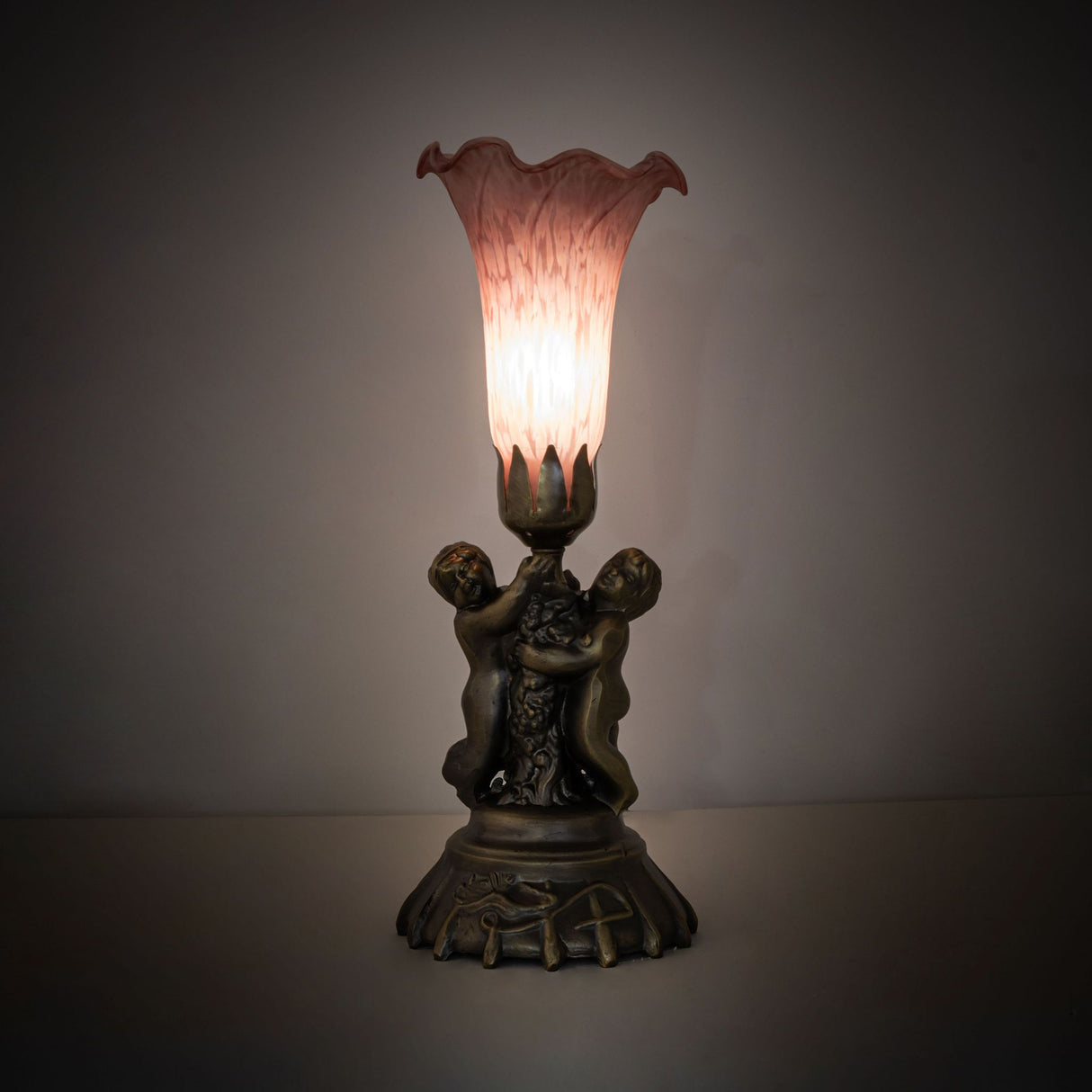 Ambient view of pink cherub accent lamp glowing softly in a dim room.