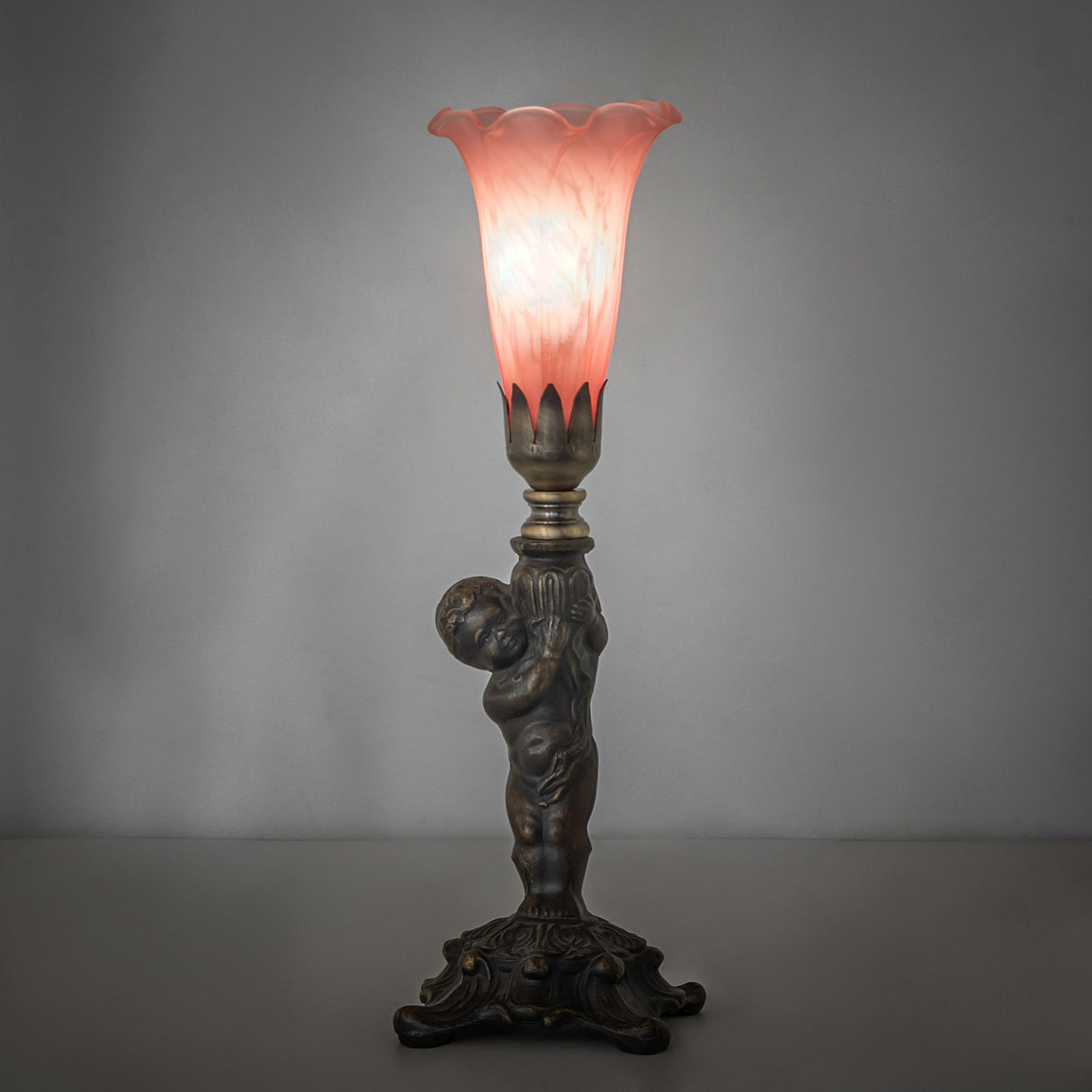 Pink Tiffany cherub mini lamp glowing softly in ambient lighting.