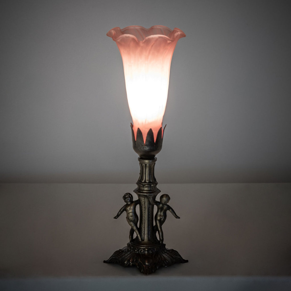Ambient view of the Pink Tiffany Pond Lily Maidens Mini Lamp casting a warm glow in a dimly lit setting.