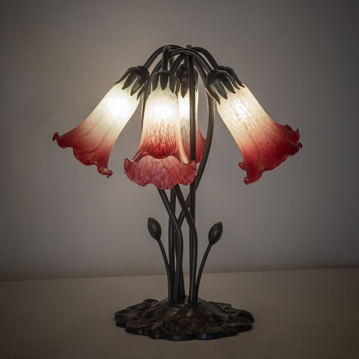 Illuminated tiffany pond lily table lamp in red and seafoam hues.