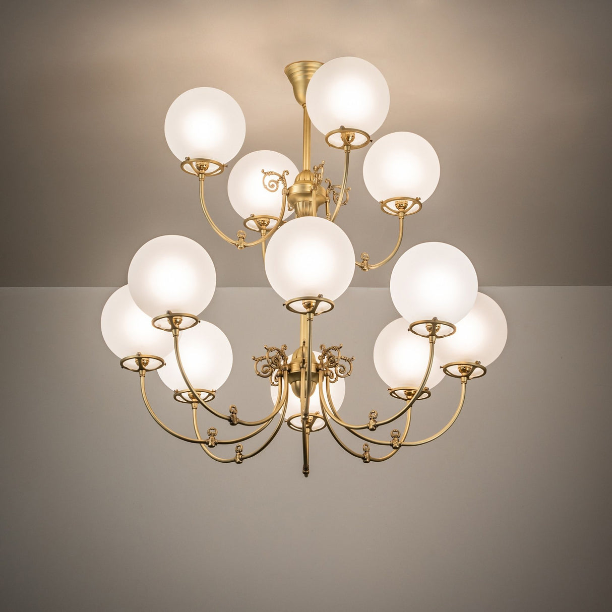 Ambient view of 12-light chandelier glowing with frosted globe glass shades.