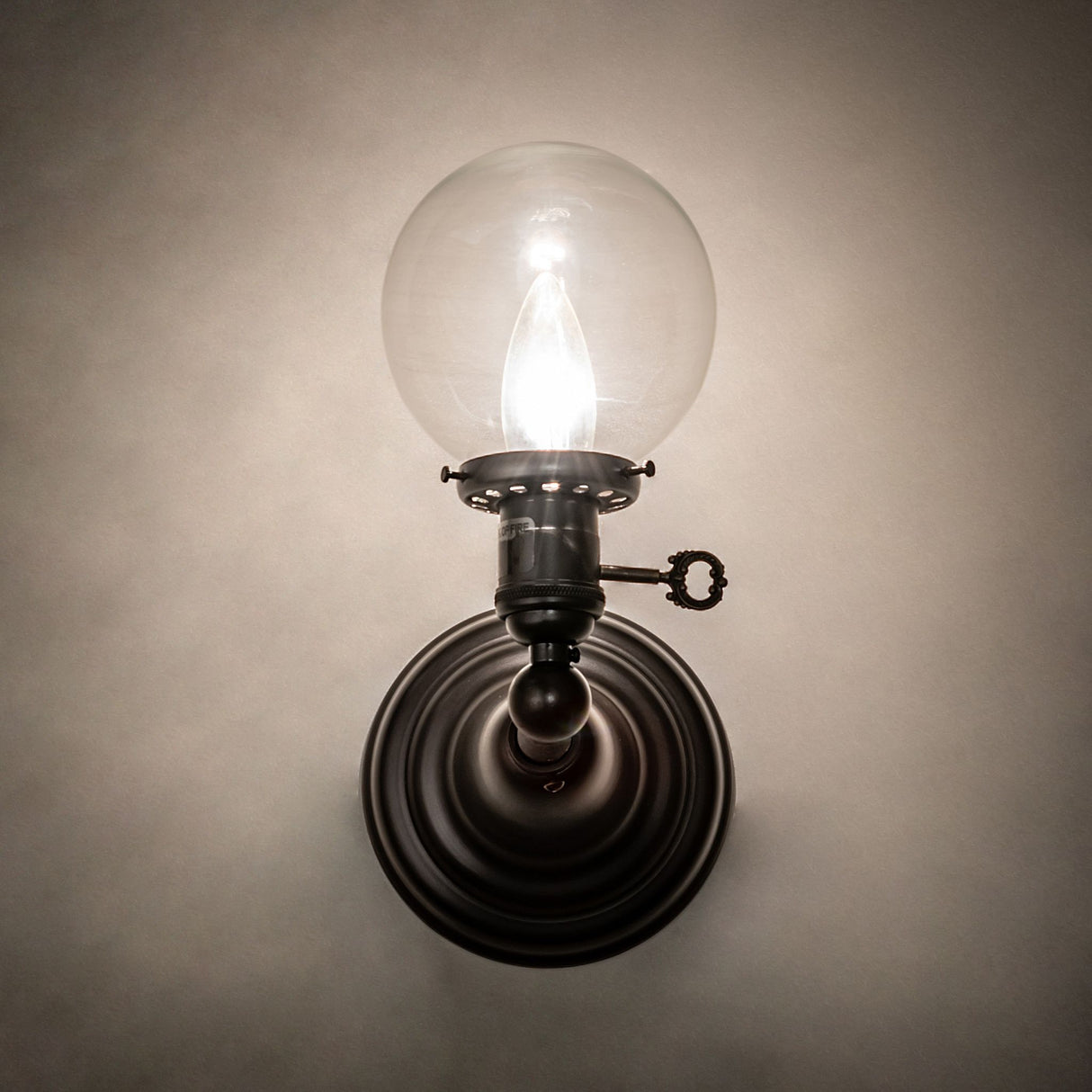 Illuminated Revival Globe Sconce showcasing clear glass globe and warm light.