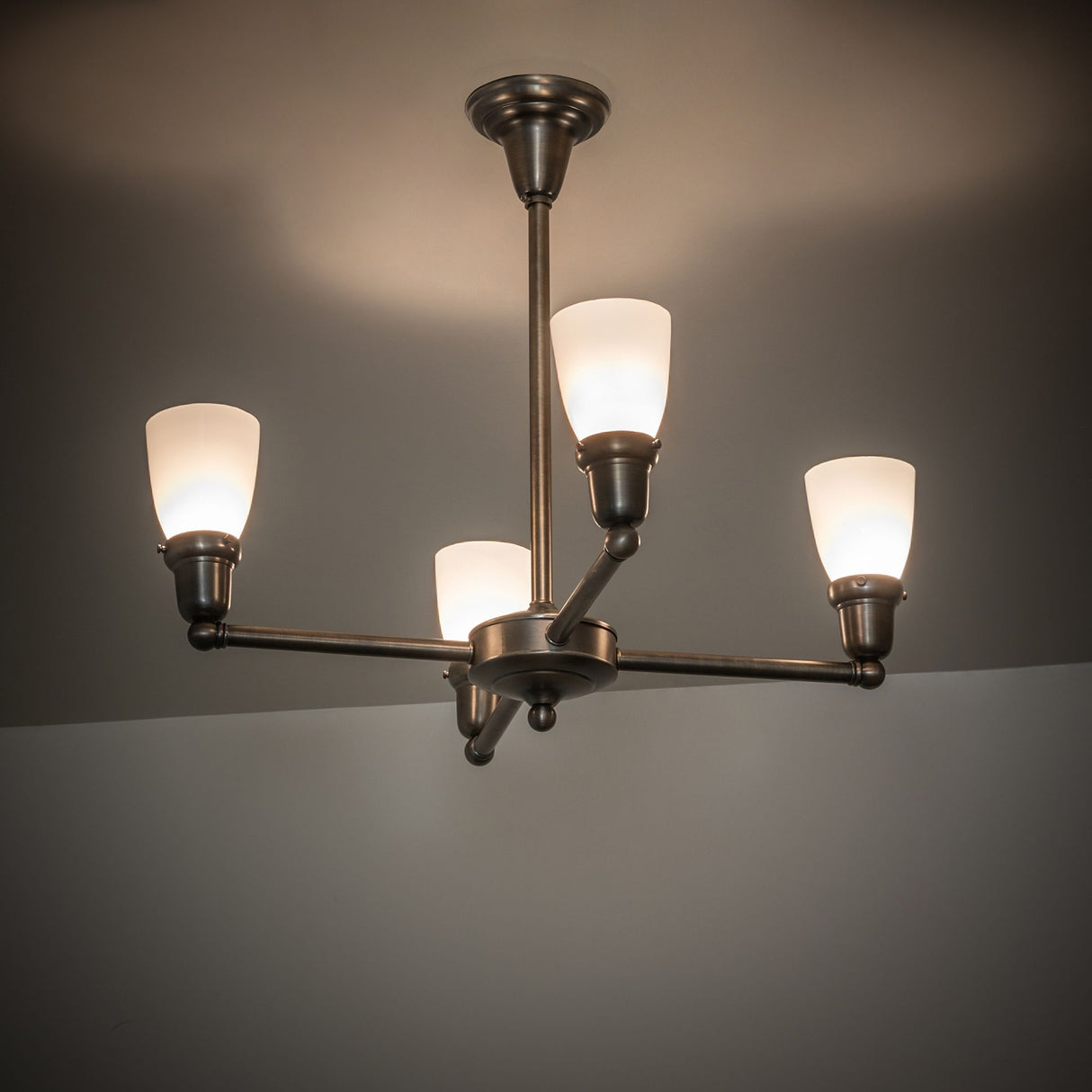 Illuminated antique brass chandelier with four glass shades.