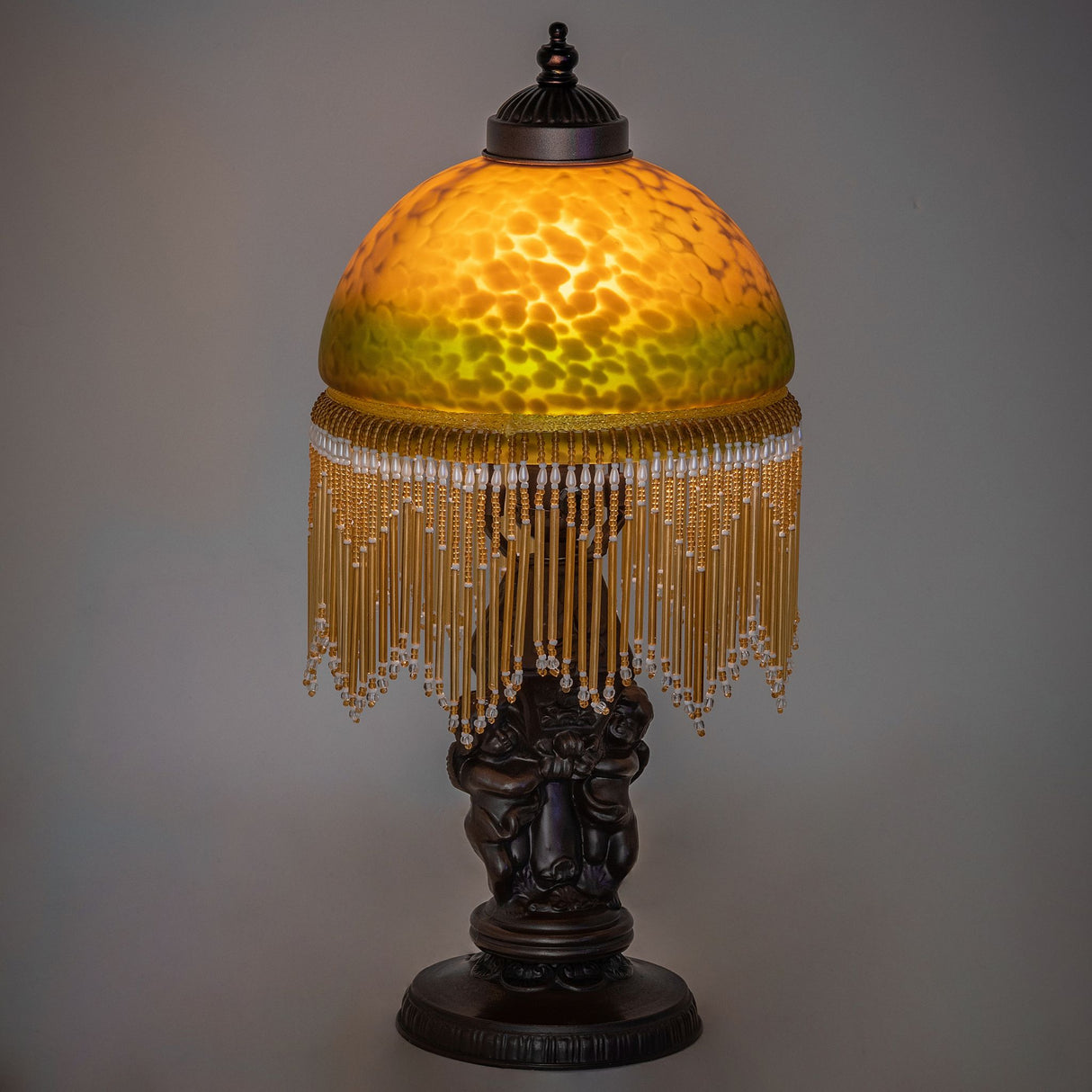 Lit view of the Roussillon Cherub Mini Lamp showcasing warm Amber and Green glow.