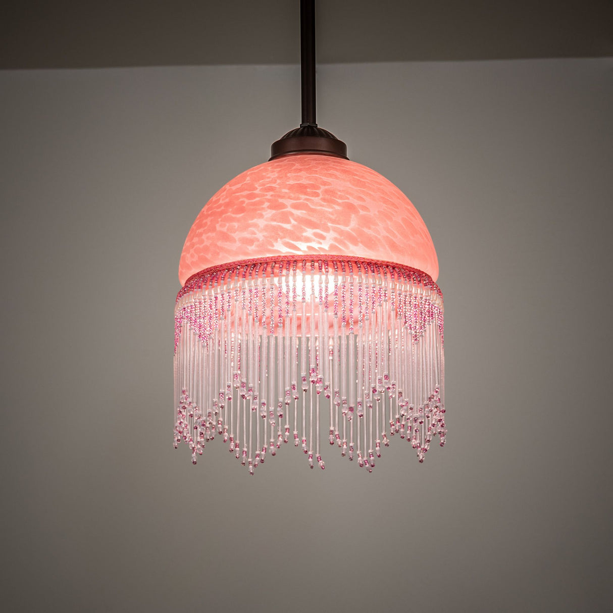 Elegant Roussillon Mini Pendant casting a warm glow with Cranberry Art Glass and Mahogany Bronze hardware.