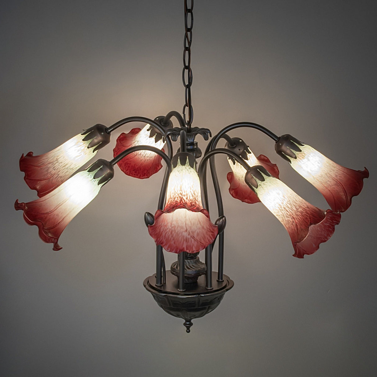 Seafoam and cranberry pond lily chandelier lit in a room.