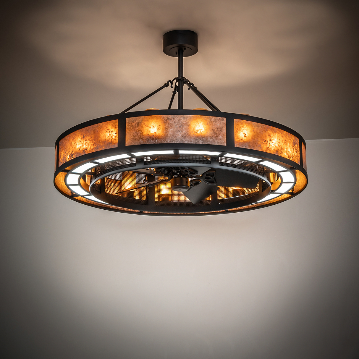 Smythe Craftsman Chandel-Air chandelier fan glowing warmly in ambient lighting.