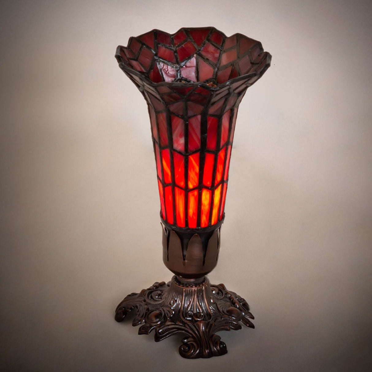 Glowing red pond lily stained glass lamp with a bronze base.
