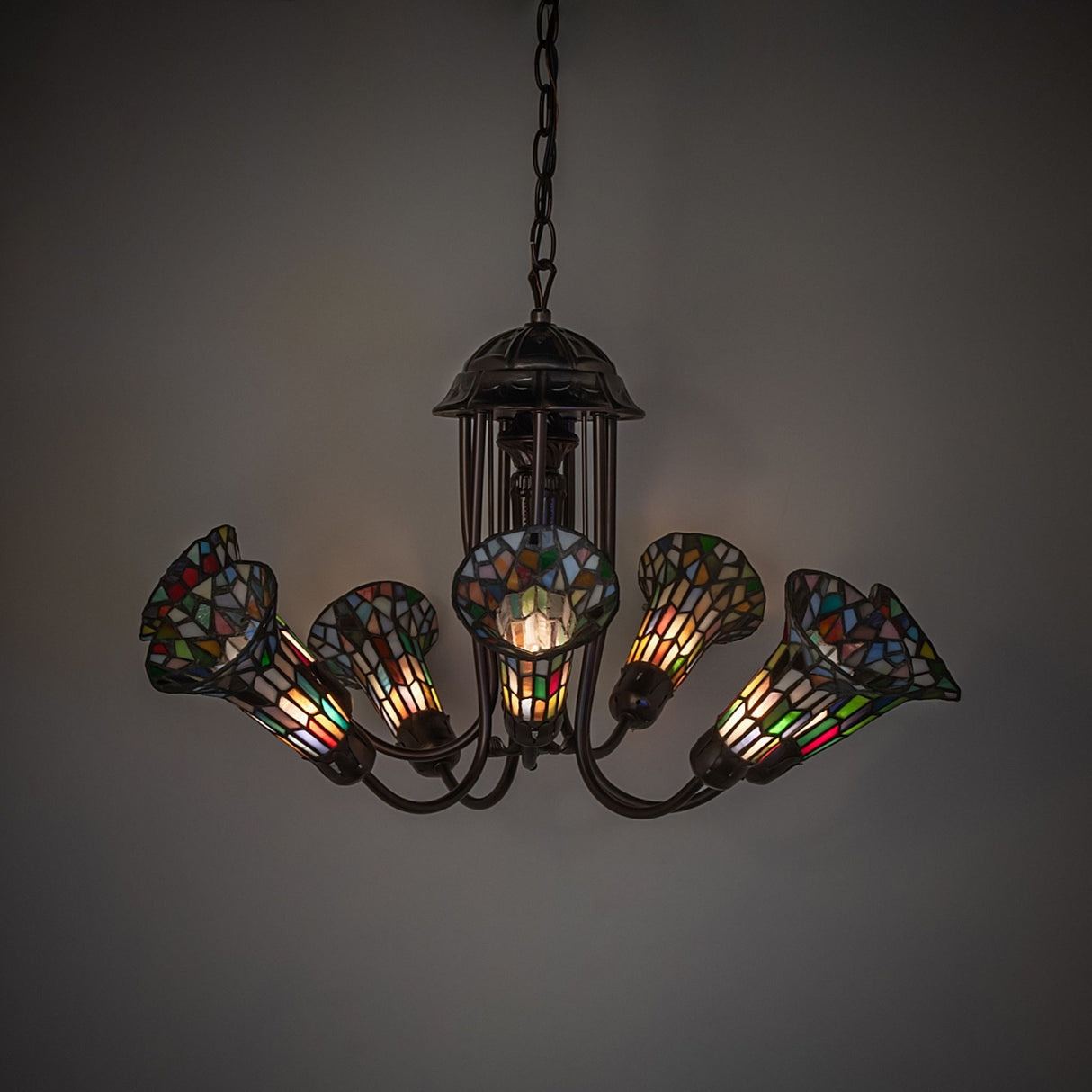 Chandelier glowing in a dimly lit room with stained glass brilliance.