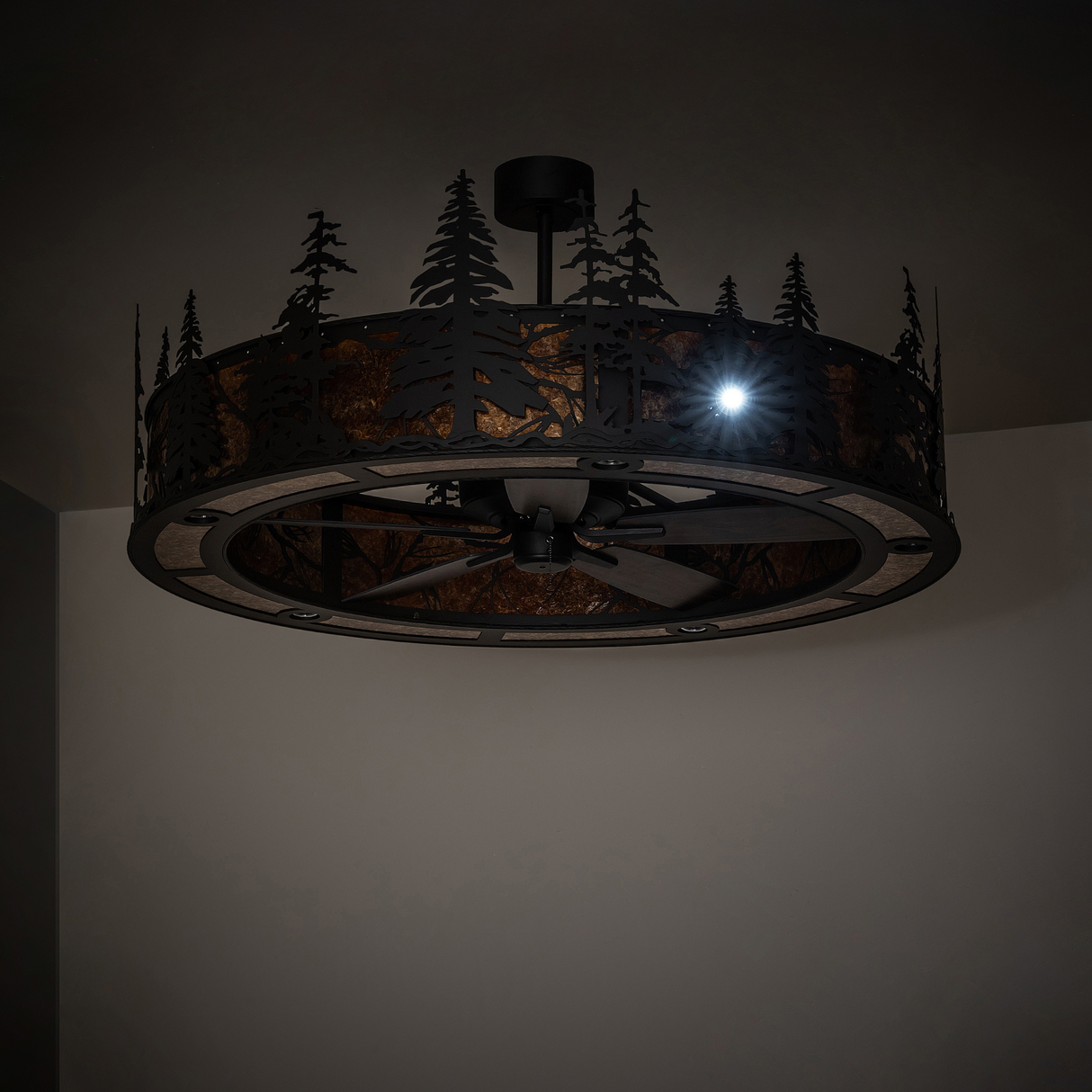 Elegant warm-lit chandelier fan showcasing detailed pine forest silhouette design.