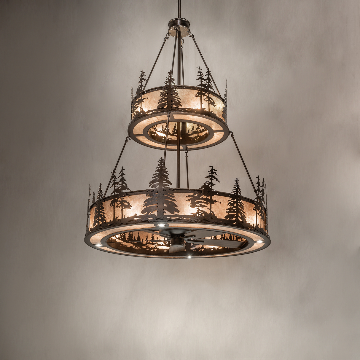 Rustic Tall Pines chandelier fan glowing against neutral wall background.