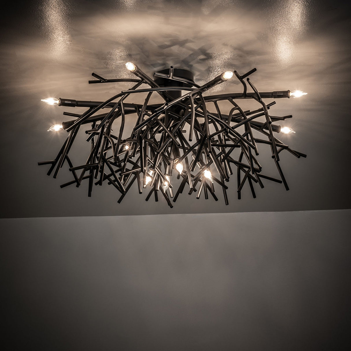 Ambient view of Thicket chandelier casting warm light with artistic branch-style metal design.