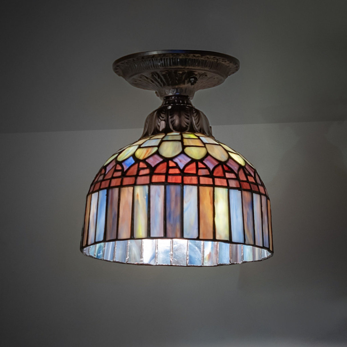 illuminated dark view of tiffany candice flushmount with vibrant stained glass colors.