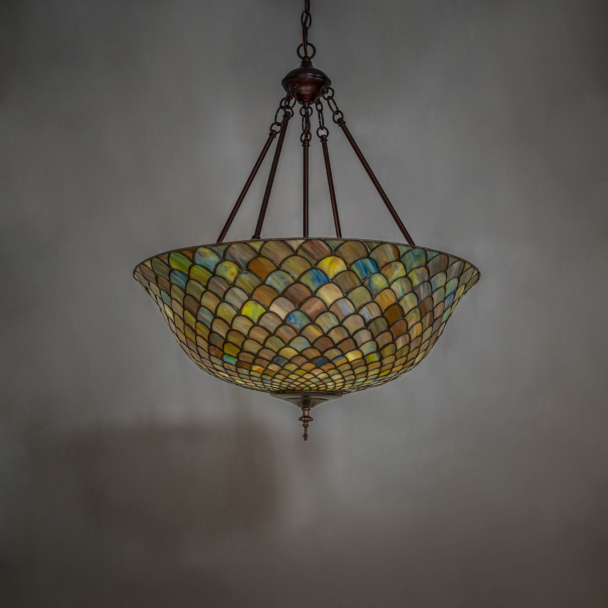 Illuminated Tiffany fishscale inverted pendant showcasing a warm glow.