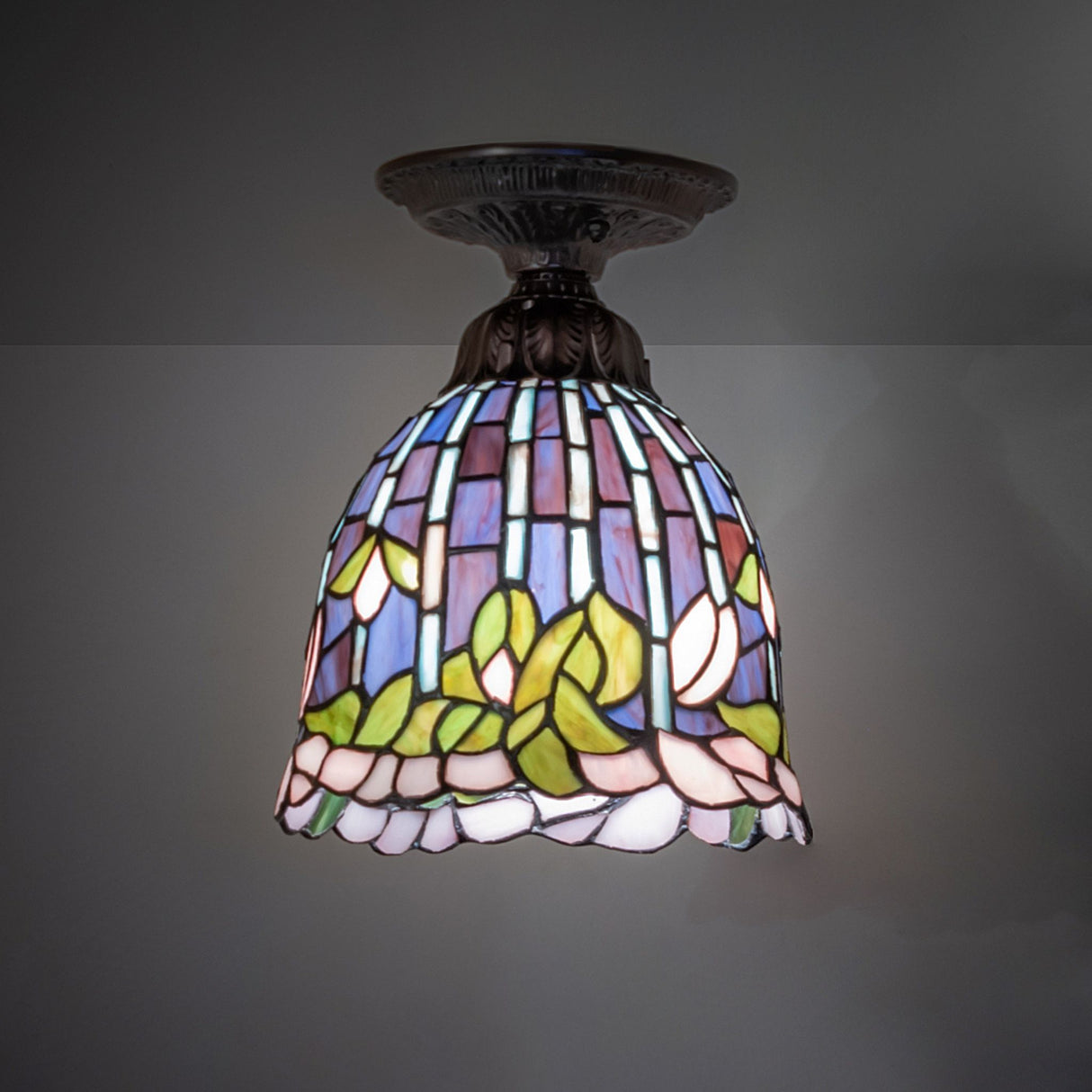 tiffany flowering lotus flushmount illuminated in a dark room, highlighting vibrant stained glass colors.