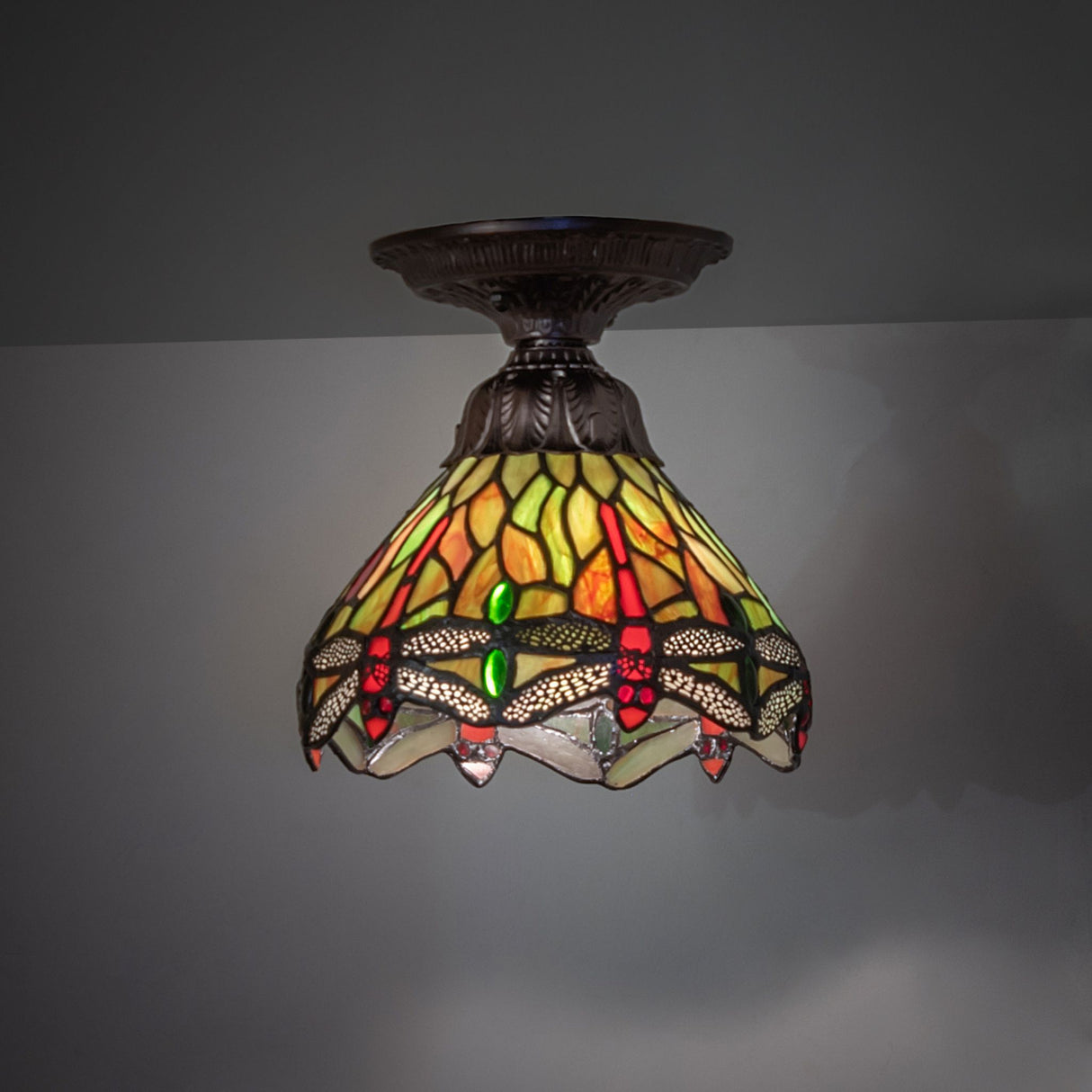 illuminated dark view of tiffany hanginghead dragonfly flushmount with vibrant stained glass colors.