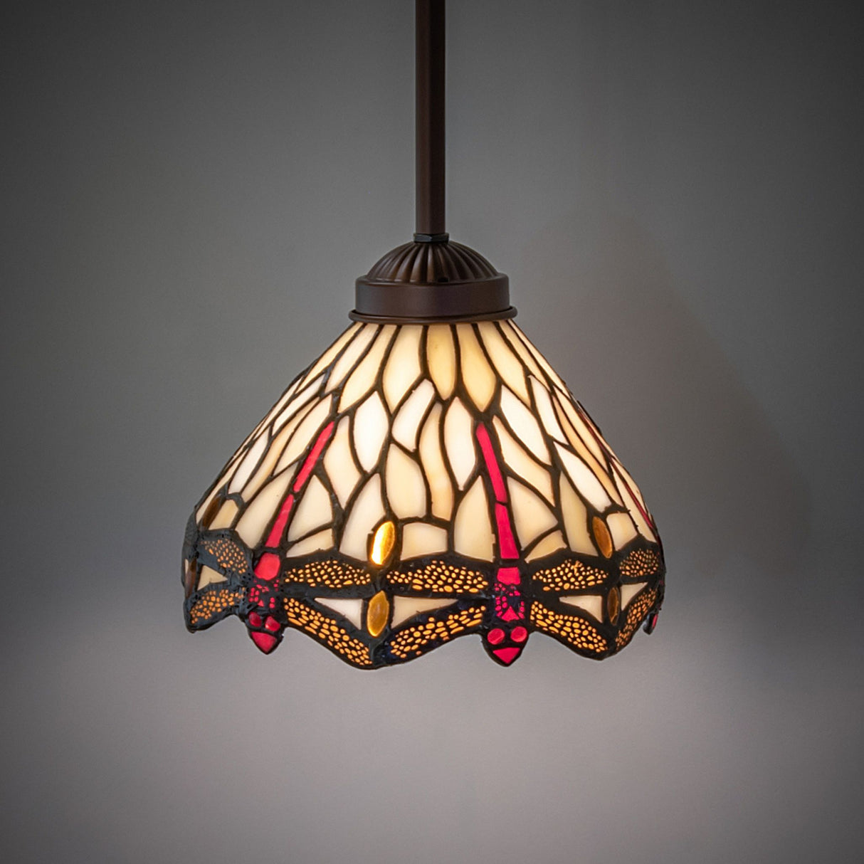 Illuminated Tiffany dragonfly mini pendant in warm tones.
