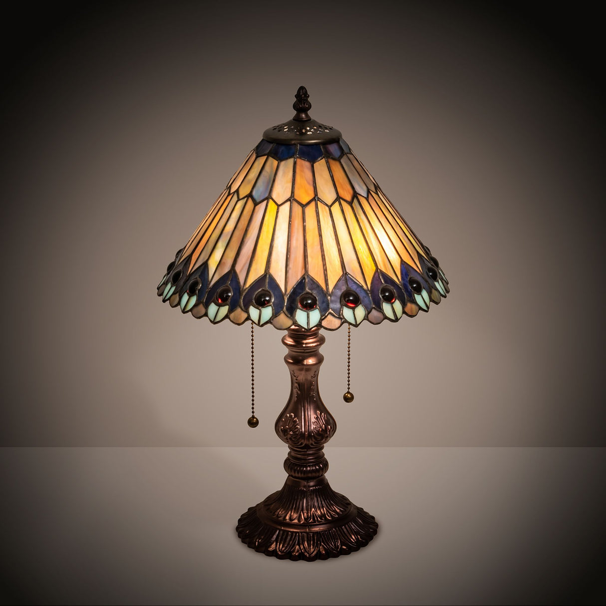 Tiffany Jeweled Peacock accent lamp casting a warm glow in a dim-lit setting.