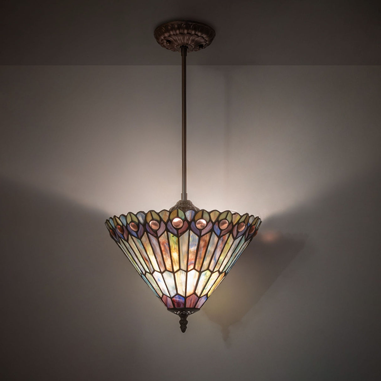 illuminated dark view of tiffany jeweled peacock pendant with vibrant hues.