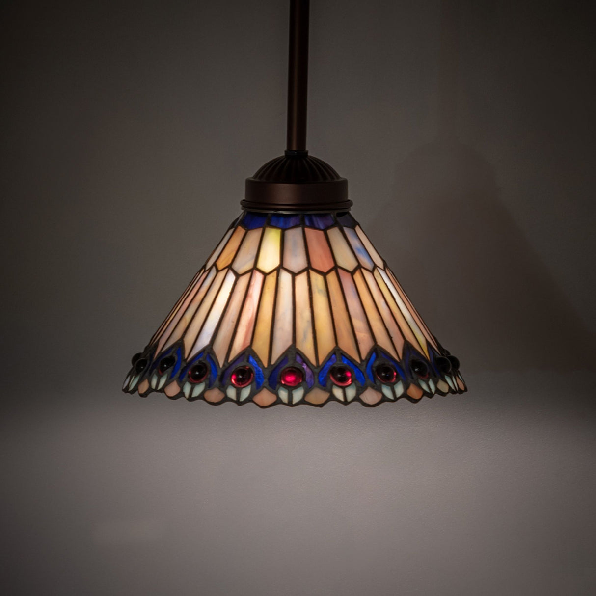Illuminated Tiffany Jeweled Peacock Mini Pendant showcasing warm, vibrant stained-glass hues.