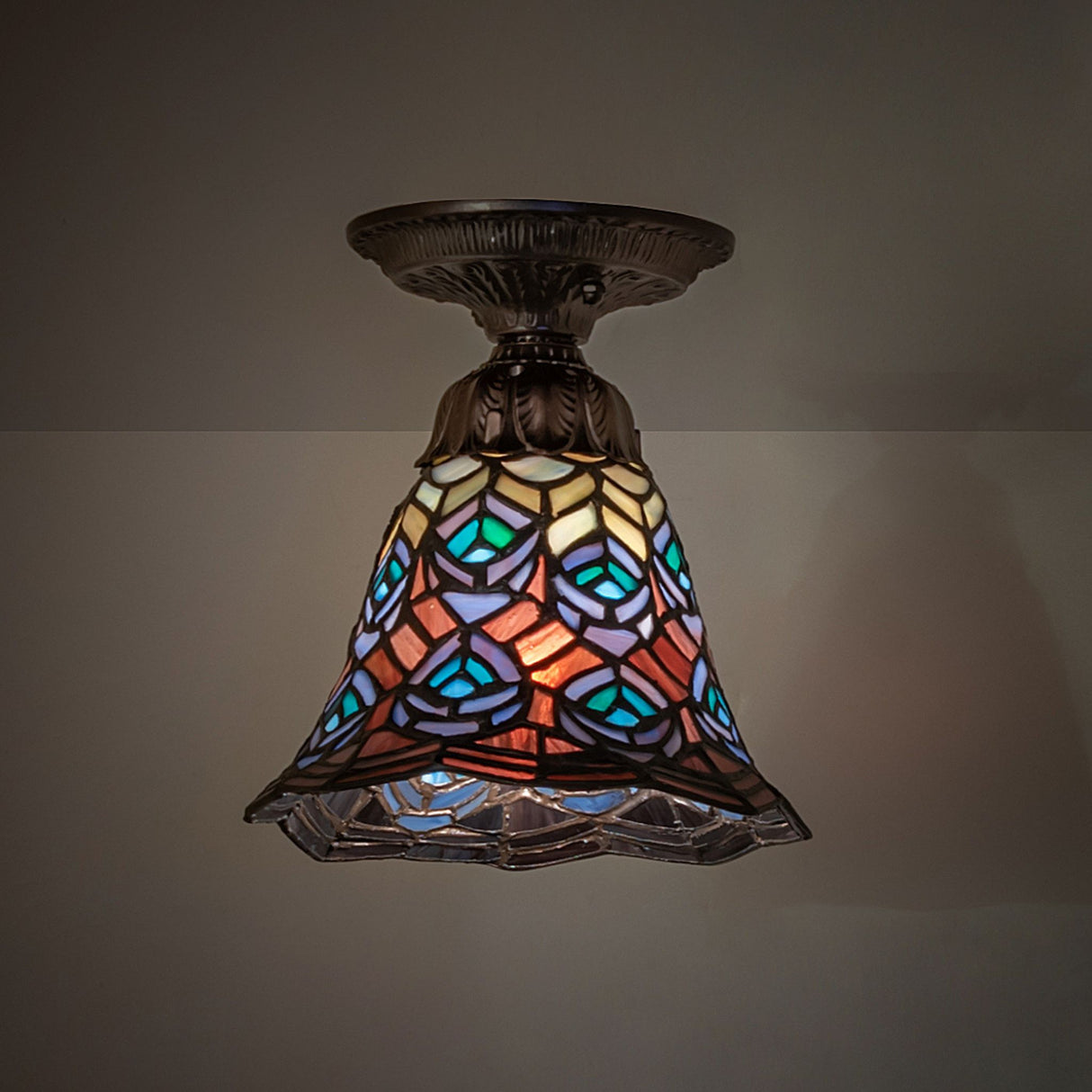 Vibrant stained glass flushmount illuminated with soft light.