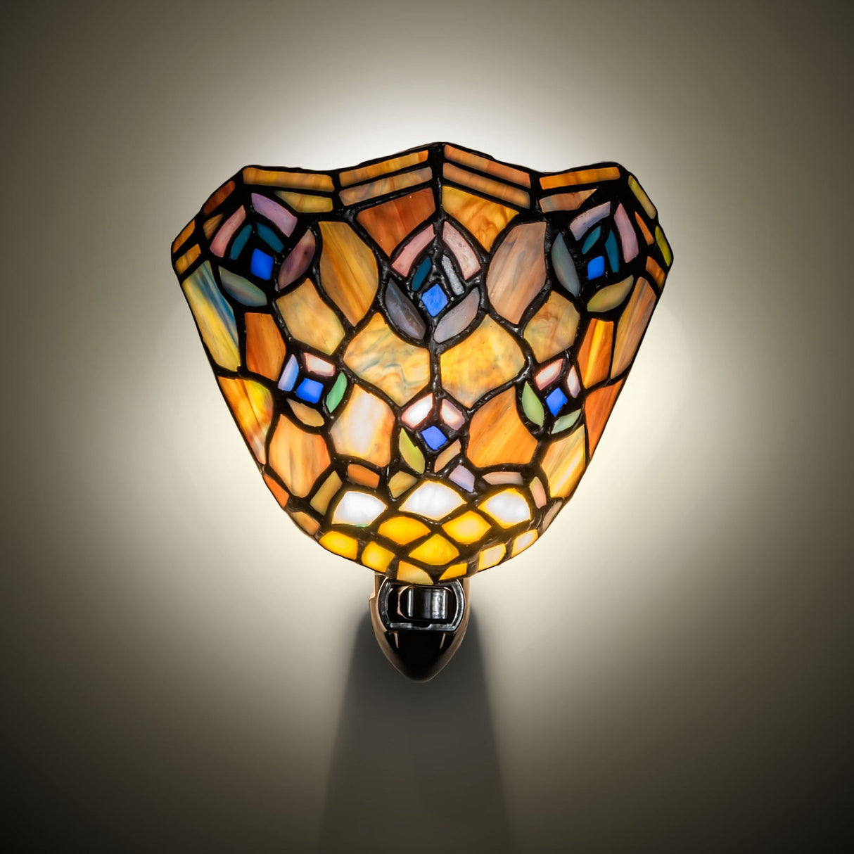 Glowing Tiffany peacock feather night light casting warm ambient light.