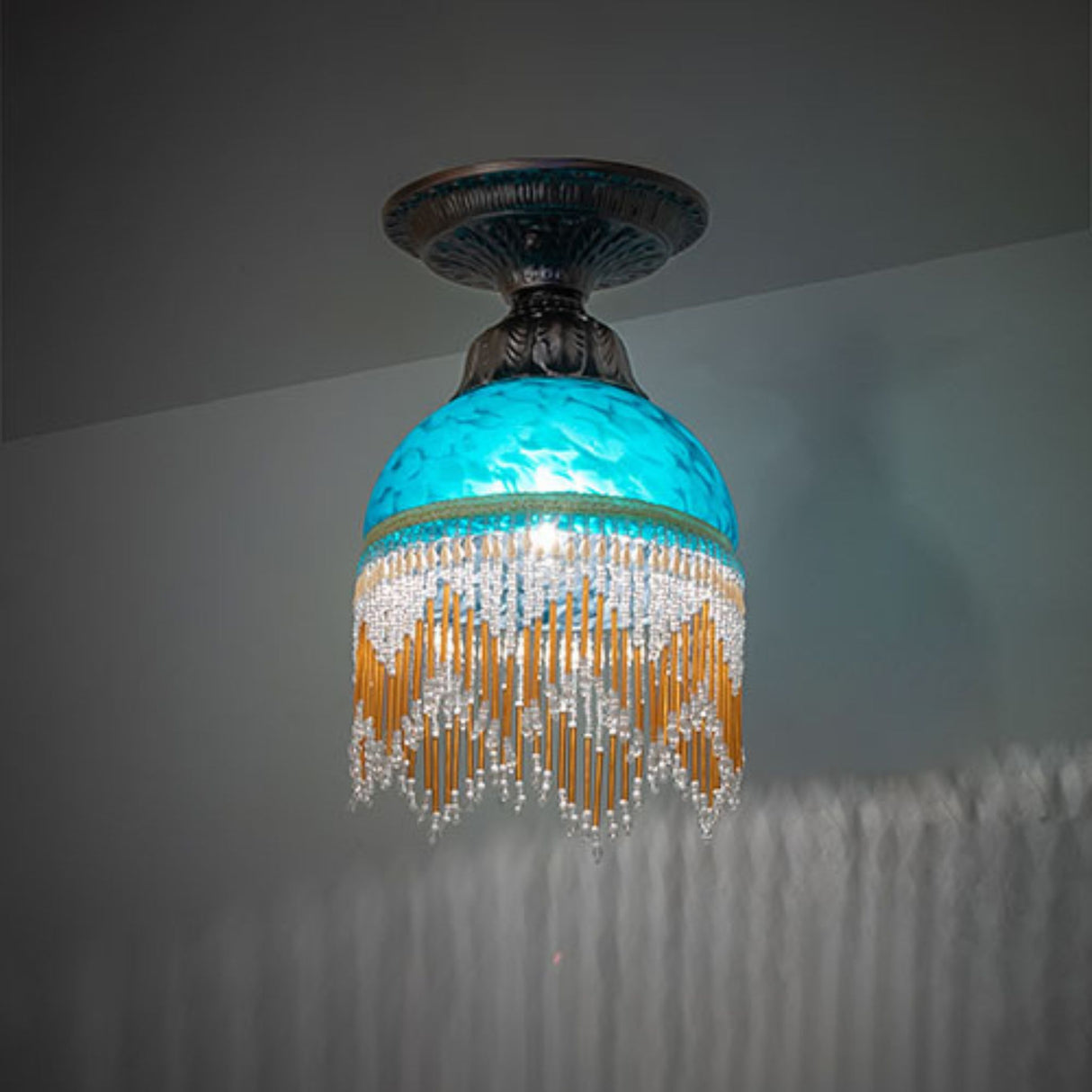 Turquoise glass flushmount light with cascading crystal and amber bead fringe.