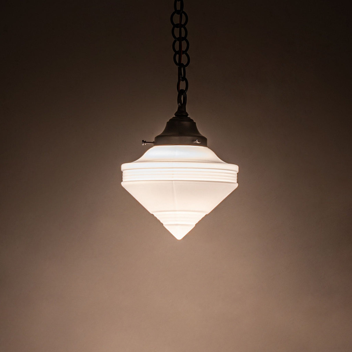 Pendant light showcasing the glowing white deco cone shade in a dim ambiance.