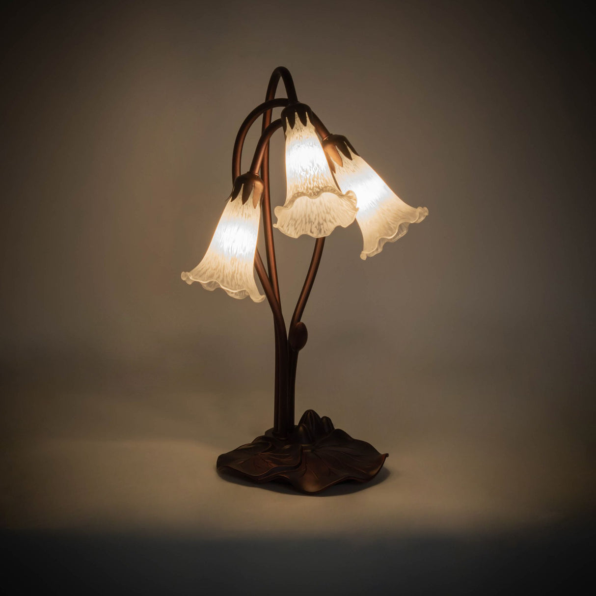 illuminated amber view of white tiffany pond lily accent lamp with glowing winter white shades.