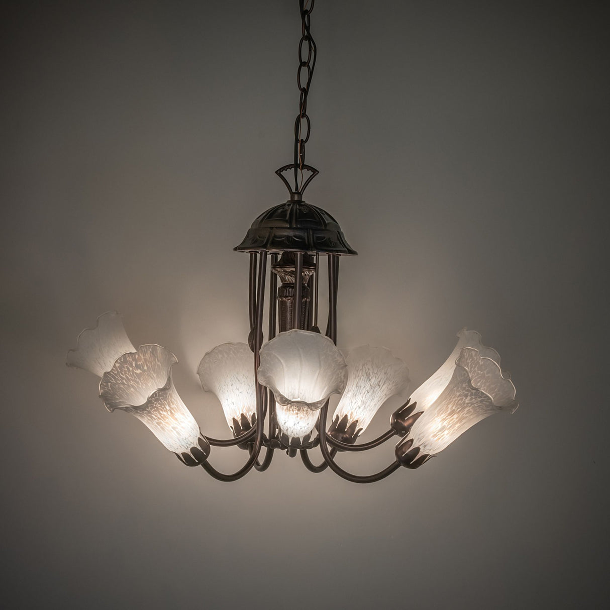 Seven-light tiffany chandelier illuminated in a dimly lit room.
