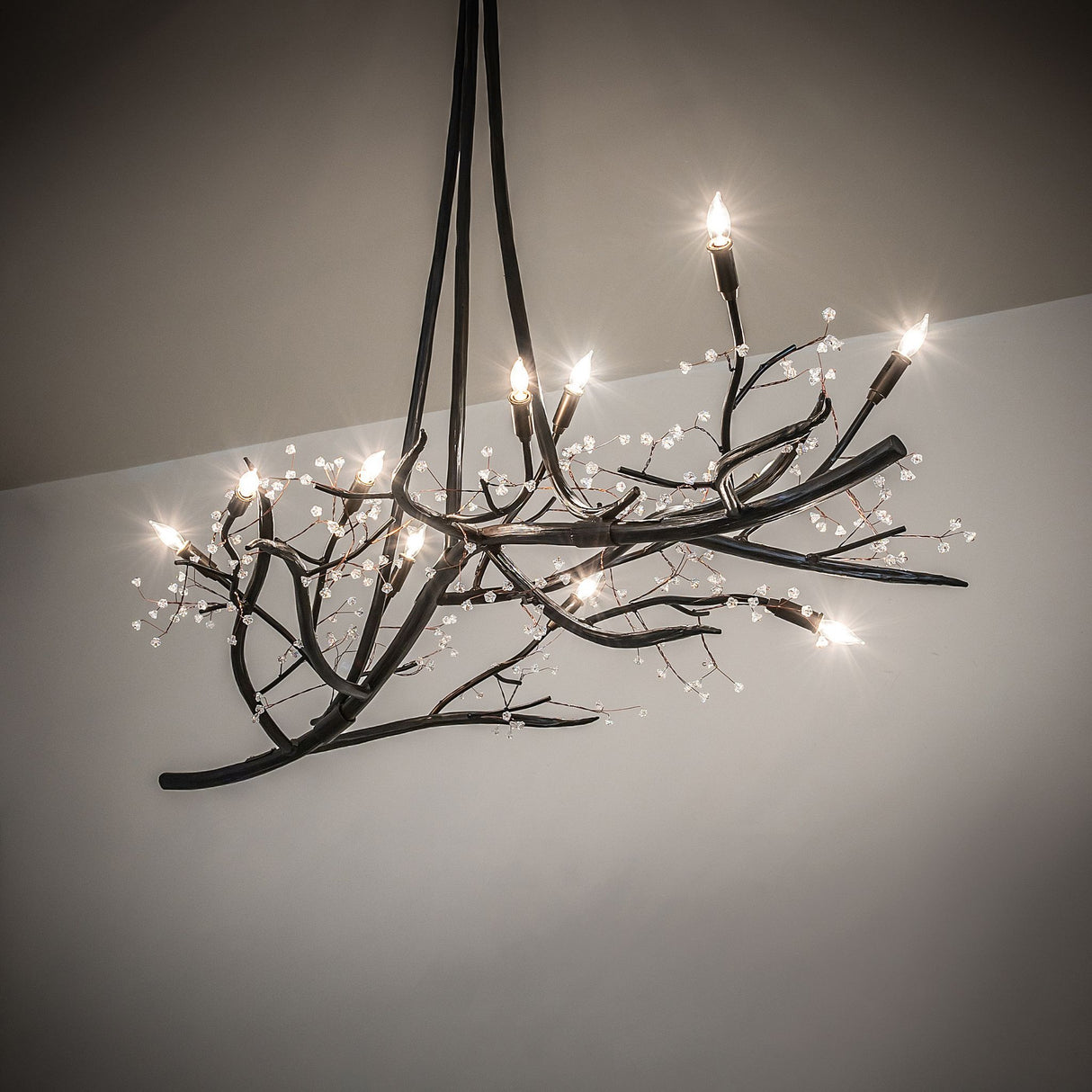 Winter solstice budding chandelier in ambient room lighting with sculptural branch design.