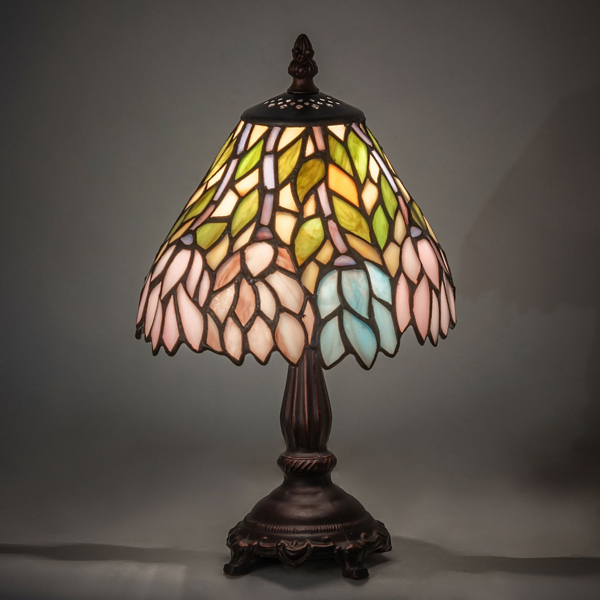 Illuminated wisteria lamp showcasing vibrant hues of blue, pink, and green art glass.