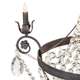 Close-up of chandelier arm with lit candle and crystal detail.