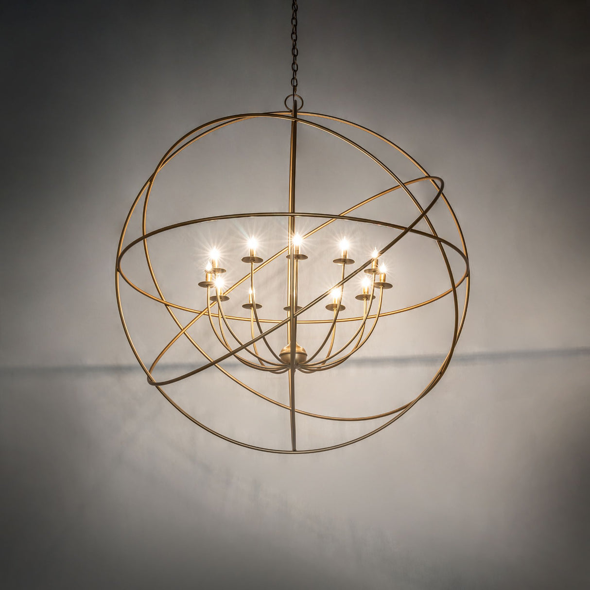 Atom style gold chandelier softly glowing in ambient room lighting.