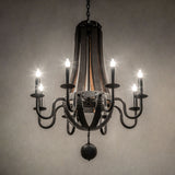Ambient view of a chandelier with a warm glow from eight faux candles on rustic wood and black metal.