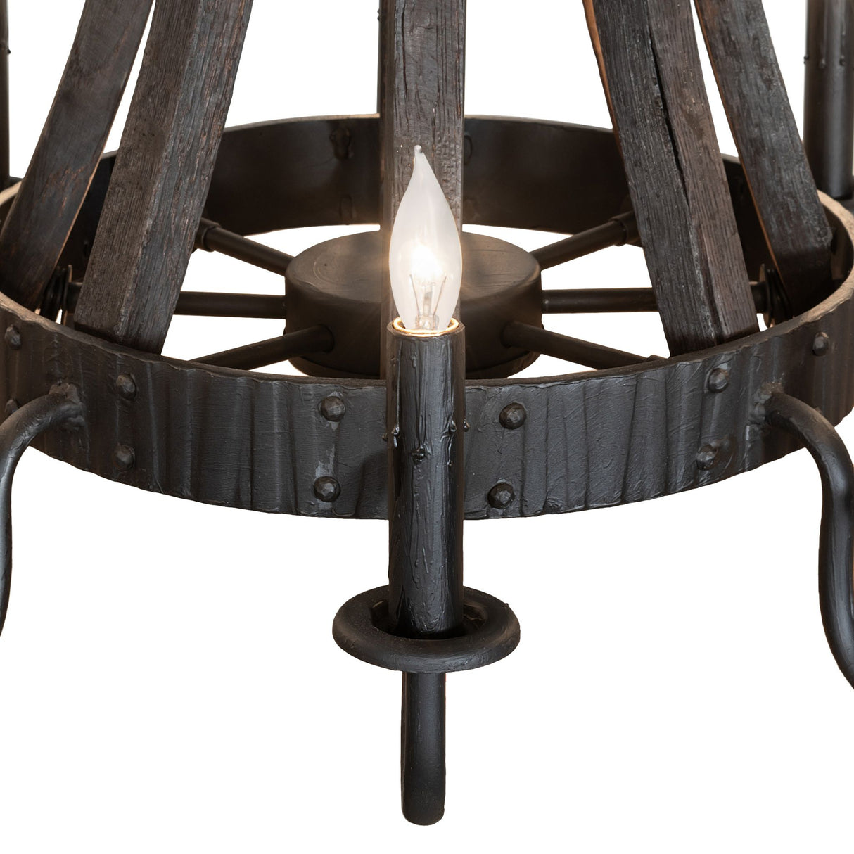 Closeup of chandelier highlighting charred wood texture, metal rivets, and candle bobeches.