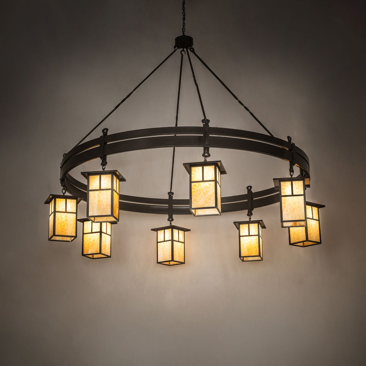 Illuminated chandelier with warm beige glass glow in dark room setting.