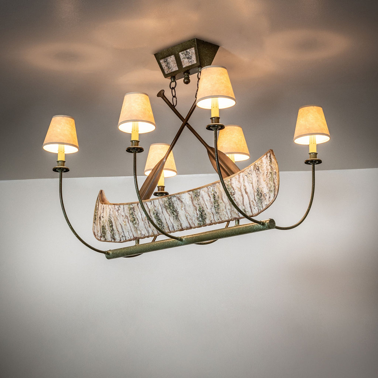 Ambient view of canoe-inspired chandelier, casting warm ambient light in rustic interiors.