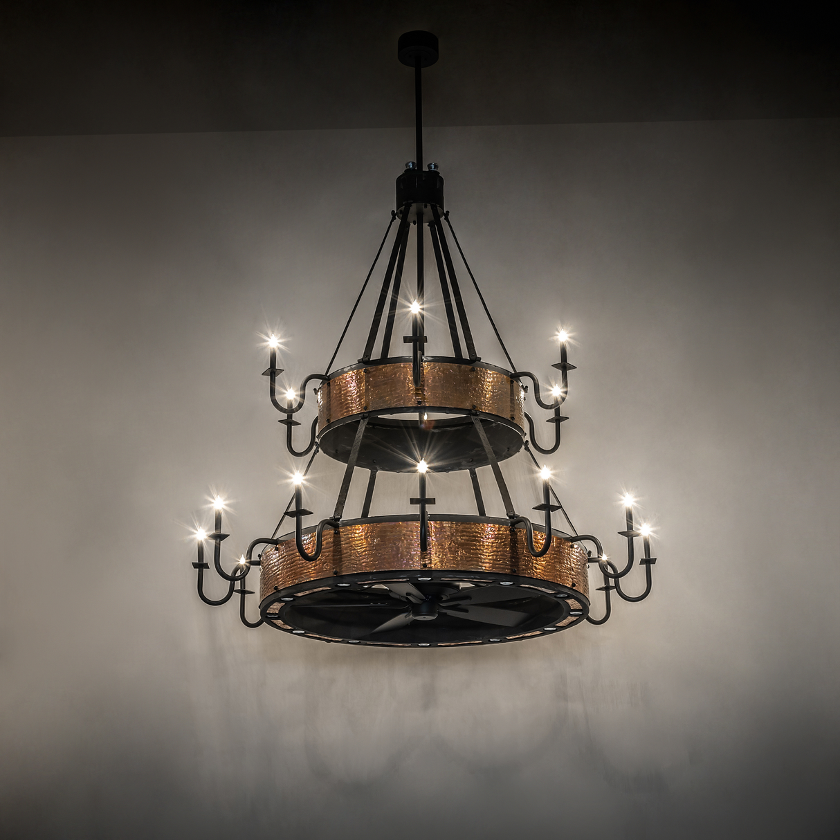 Costello two-tier chandelier fan glowing softly in dark room.