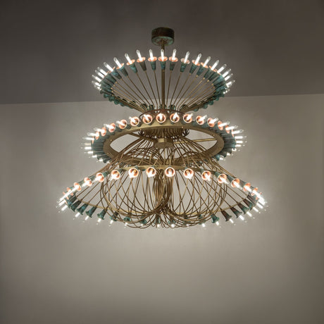 Ambient view of 108-light chandelier glowing in room with brushed brass and copper tiers.
