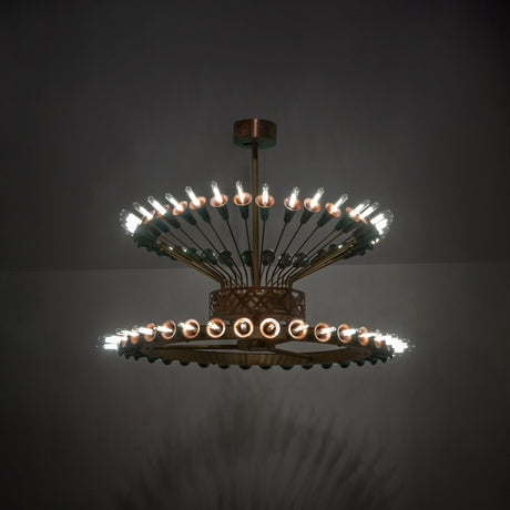 Coyle 72 light two-tier chandelier glowing in room setting with brass and verdigris copper details.