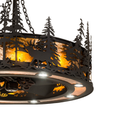Closeup lit view showing elk and pine detail illuminated by amber light.