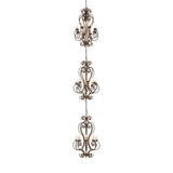 Lit view of three-tier chandelier with scrollwork design and faux candlelights.