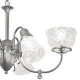 Close-up of glass shade and curved metal arm on gas and electric 6 light chandelier.