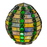 Lit view of the jeweled beehive shade with vibrant emerald and earthy tones glowing warmly.