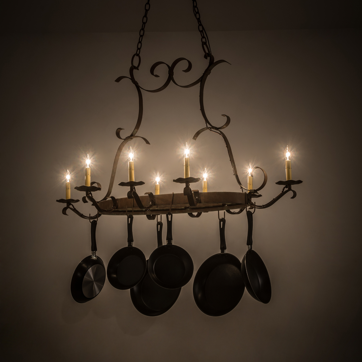 Laramie pot rack chandelier illuminated in dimly lit kitchen.